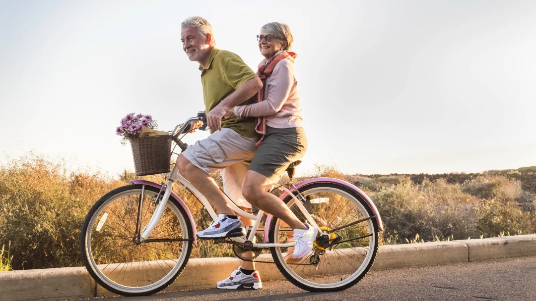 A couple rides a bike together.