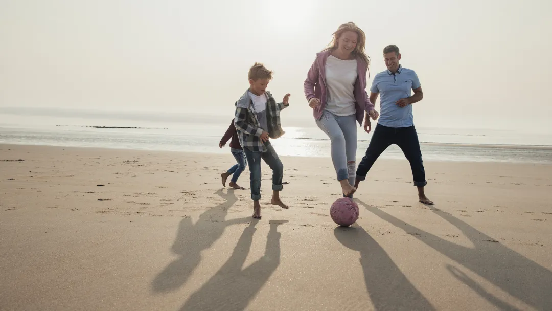 A family plays a friendly game of soccer on the beach