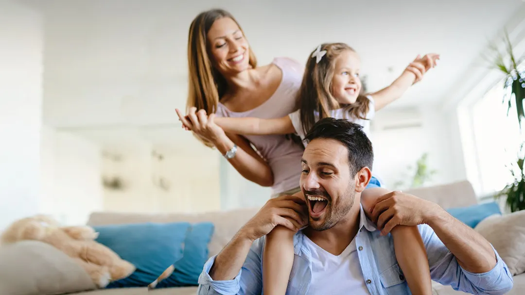 Man laughing carrying his daughter on his shoulders