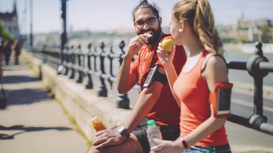 Two runners eat a healthy snack.