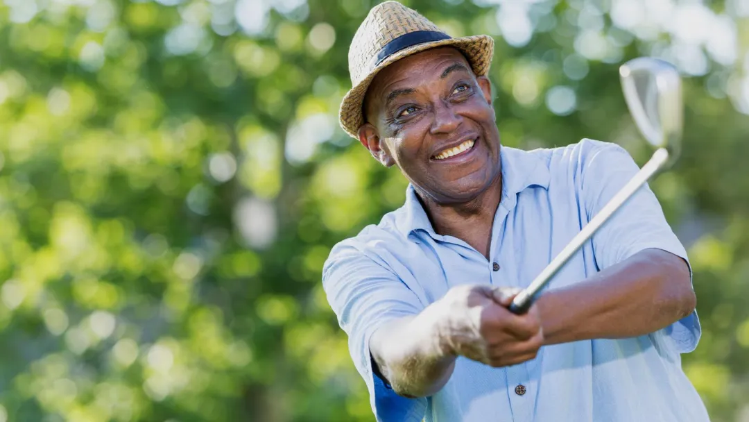 Mature golfer teeing off