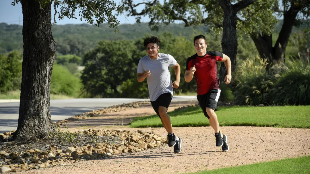 Two young men running outside on a path.