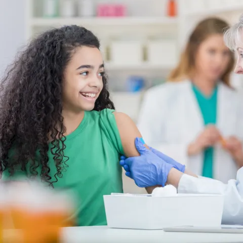 A preteen gets her first HPV vaccine shot from a nurse.