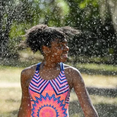 A tween plays in a sprinkler