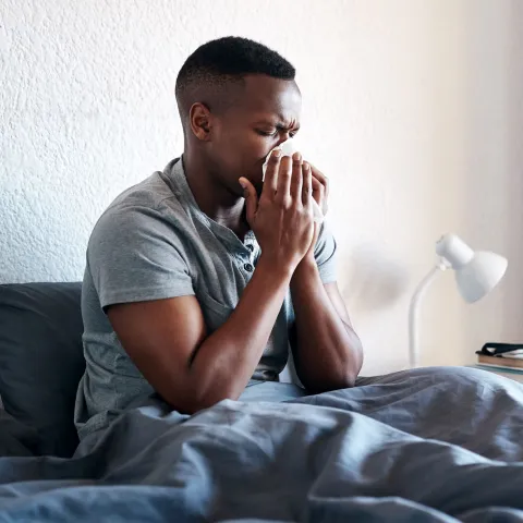A man blowing his nose at home.