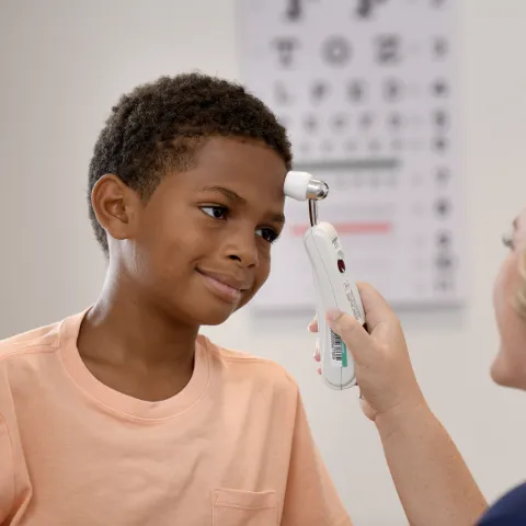 A Young Patient Smiles as a Primary Care Nurse Checks His Tempature