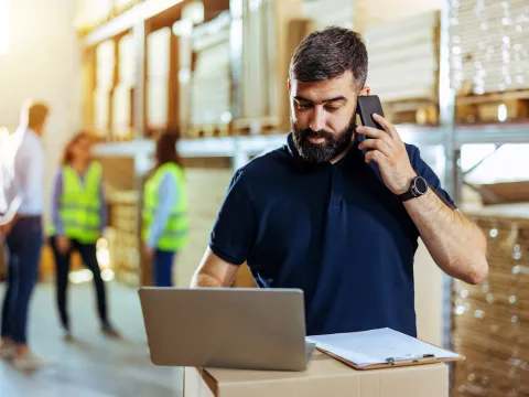 Man on cellphone looking at laptop.