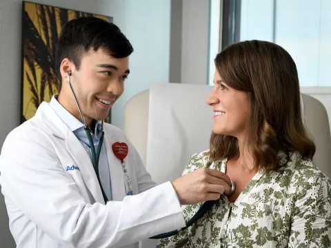 Doctor using stethescope to listen to female patient's heart