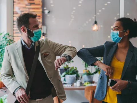 Masked coworkers elbow bump