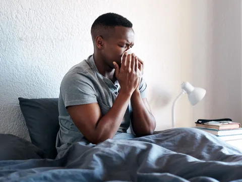 A man blowing his nose at home.
