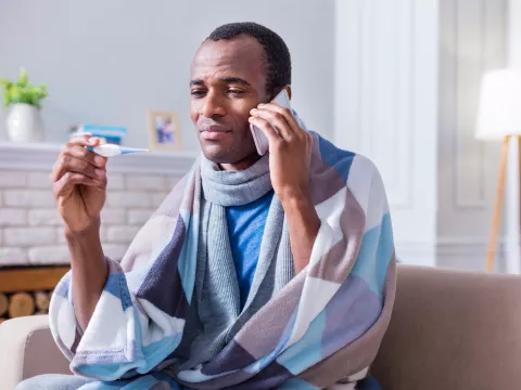 A man with a fever calling his doctor from home.