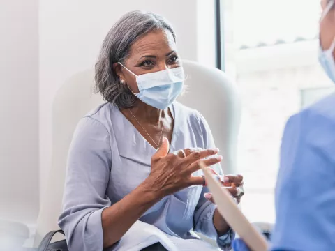 A mature woman visiting her doctor while wearing a mask.