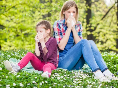Two ladies experiencing allergy symptoms while sitting outside.